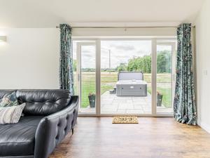 a living room with a leather couch and a sliding glass door at Kings Lodge in Neatishead