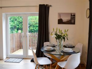 a dining room with a glass table and white chairs at Bryn Aled in Llanfachreth