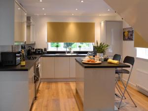 a kitchen with white cabinets and a island with a table at Bryn Aled in Llanfachreth