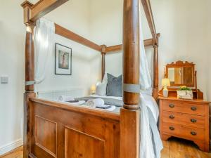 a wooden canopy bed in a bedroom with a dresser at The Dairy - Ukc3780 in Hickling +3 photos