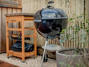 a grill sitting next to a wooden table and a fence at Copse Lodge in Eling