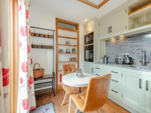 a kitchen with white cabinets and a table and chairs at Copse Lodge in Eling +10 photos
