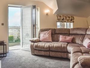 a living room with a brown couch with pink pillows at Kinneret Apartment in Silsden
