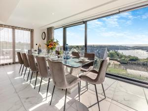 a dining room with a table and chairs and large windows at Seabreeze in Saint Mawes