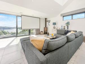 a living room with a gray couch and a large window at Seabreeze in Saint Mawes
