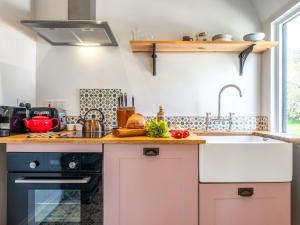 a kitchen with pink cabinets and a sink at The Old Press - Uk50806 in Halesworth
