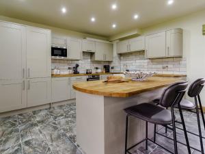 a kitchen with white cabinets and bar stools at The Millhouse - Uk32510 in Marloes