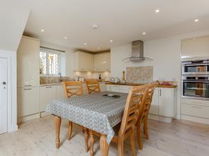 a kitchen with a table and chairs and a kitchen with white cabinets at Willow Cottage - Uk39244 in Inverness