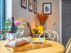 a table with a bottle of wine and a loaf of bread at Hayloft - Uk49529 in Buchlyvie