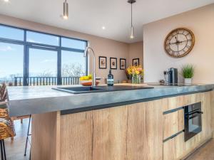 a kitchen with a large counter with a clock on the wall at Hayloft - Uk49529 in Buchlyvie +14 photos