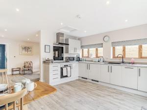 a kitchen with white cabinets and a dining room at Wisteria Lodge - Ukc5804 in Shelfanger +8 photos