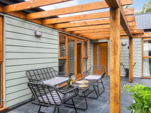a patio with chairs and a table and a wooden pergola at North Farm Lodges in East Mersea