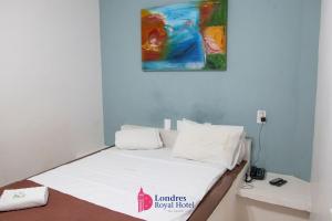 a bed in a room with a painting on the wall at Londres Royal Hotel - Cama de alvenaria in Londrina
