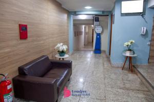 a waiting room with a leather couch in a hallway at Londres Royal Hotel - Cama de alvenaria in Londrina