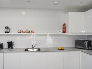 a white kitchen with a sink and a microwave at Rose Cottage in Bardon Mill +12 photos