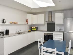 a kitchen with white cabinets and a blue table at Rose Cottage in Bardon Mill