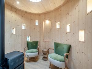 two green chairs in a room with wooden walls at The Treehouse Caerlaverock - Uk45028 in Carsethorn