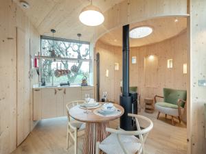 a room with a stove and a table and chairs at The Treehouse Caerlaverock - Uk45028 in Carsethorn