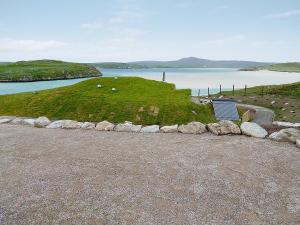 a bench sitting on a hill next to a body of water at Beach Bay Cottage in Mangersta +2 photos