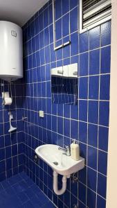 a blue tiled bathroom with a sink and a window at Baklava in Sarajevo