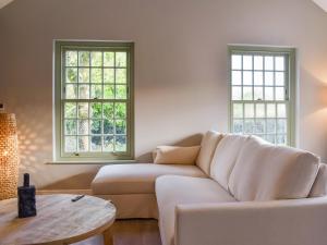 a living room with a white couch and two windows at Bluebell Cottage in Bodmin