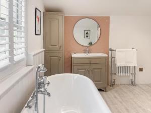 a bathroom with a tub and a sink and a mirror at Bluebell Cottage in Bodmin