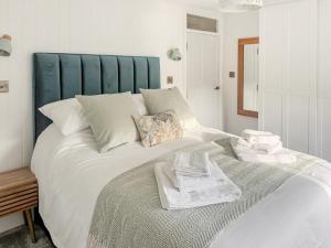 a large white bed with a blue headboard in a room at Bluebell Cottage in Bodmin +11 photos