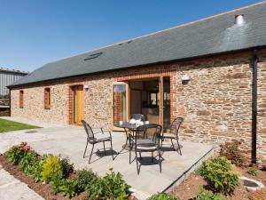 a patio with a table and chairs in front of a building at Meadow Barn - Blackdown Farm in Blackawton