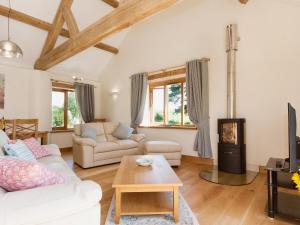 a living room with white furniture and a wood stove at Meadow Barn - Blackdown Farm in Blackawton +4 photos