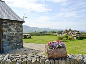 a garden with a stone building and flowers in a box at Ysgubor in Harlech