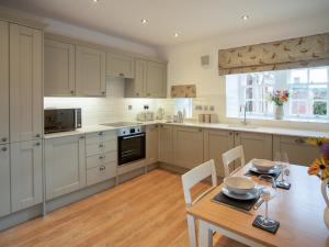 a kitchen with white cabinets and a wooden table at Stableyard Studio - Uk7173 in Carronbridge