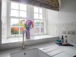 a kitchen sink with a vase of flowers in a window at Stableyard Studio - Uk7173 in Carronbridge