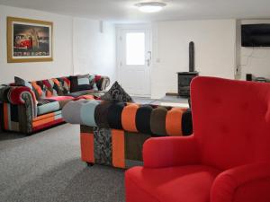 a living room with two couches and a red chair at Awelfa - On7 in Aberaeron