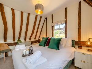a bedroom with a large white bed with green pillows at Oak Tree Cottage in Quidenham