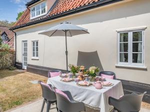 a table with pink chairs and an umbrella at Oak Tree Cottage in Quidenham
