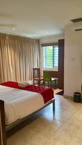 a bedroom with a bed and a chair and a window at Hotel Amulya Royal Inn in Bangalore