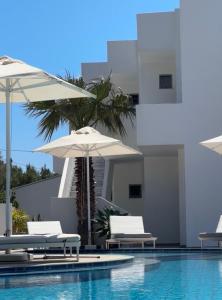 a swimming pool with chairs and umbrellas in front of a building at Glykeria Hotel in Elafonisi