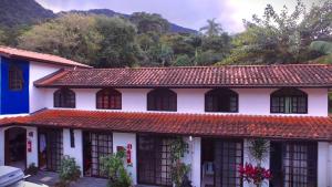 a white house with a red tile roof at Pousada Em Busca do Sol in Trindade