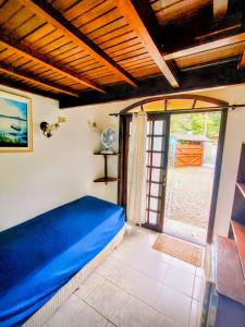 a bedroom with a blue bed and a sliding glass door at Pousada Em Busca do Sol in Trindade