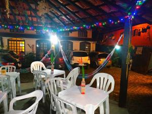a room with white tables and white chairs and lights at Pousada Em Busca do Sol in Trindade
