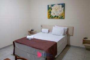a small bedroom with a bed with white sheets at Londres Royal Hotel in Londrina +14 photos