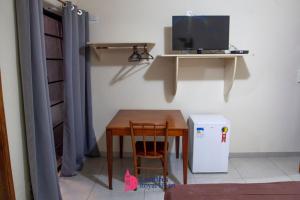 a room with a table and a tv on a wall at Londres Royal Hotel in Londrina