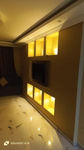 a room with a tv on the wall with yellow lights at Ashraf Residential Complex in Luxor