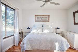 a white bedroom with a bed and a ceiling fan at Moodemere Lake House in Rutherglen