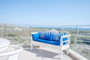 a blue and white chair on a balcony with a view of the ocean at Apeiron Akrotiri - Apeiron Hotels in Akrotiri