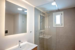 a bathroom with a sink and a shower and a mirror at Apeiron Akrotiri - Apeiron Hotels in Akrotiri