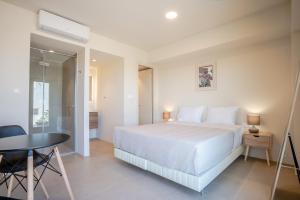 a bedroom with a white bed and a table at Apeiron Akrotiri - Apeiron Hotels in Akrotiri