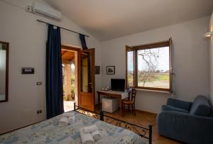 a room with a bed and a desk and a window at Agriturismo Il Capannone in Montemerano