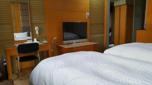 1 dormitorio con 1 cama y escritorio con TV en 雲林斗六御花園汽車旅館, en Douliu