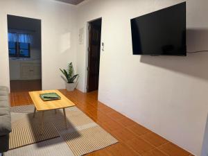 a living room with a table and a television on a wall at Siam phangan in Ko Phangan